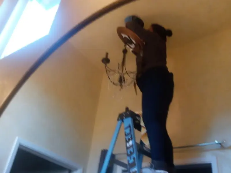 Electrician installing a chandelier in a Heyburn residence